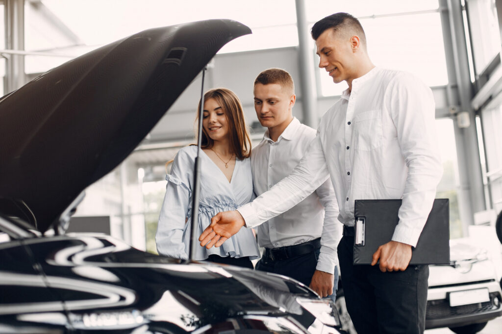 Pareja joven observando el interior del auto, junto al vendedor. 